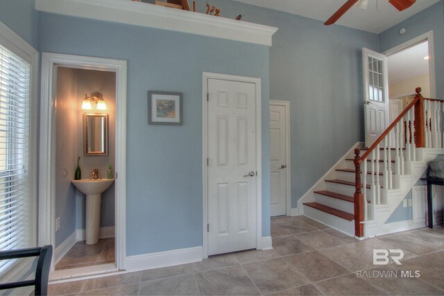 interior space with a ceiling fan, tile patterned flooring, and baseboards