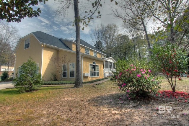 view of side of home with a lawn, a sunroom, and stucco siding