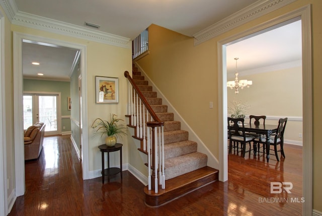 staircase featuring baseboards, wood finished floors, visible vents, and crown molding