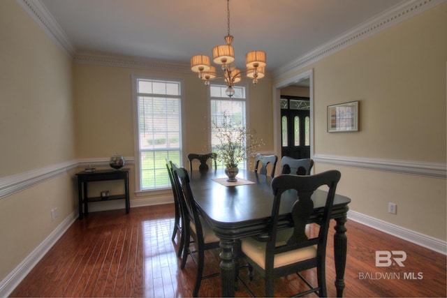 dining space with ornamental molding, a chandelier, dark wood finished floors, and baseboards