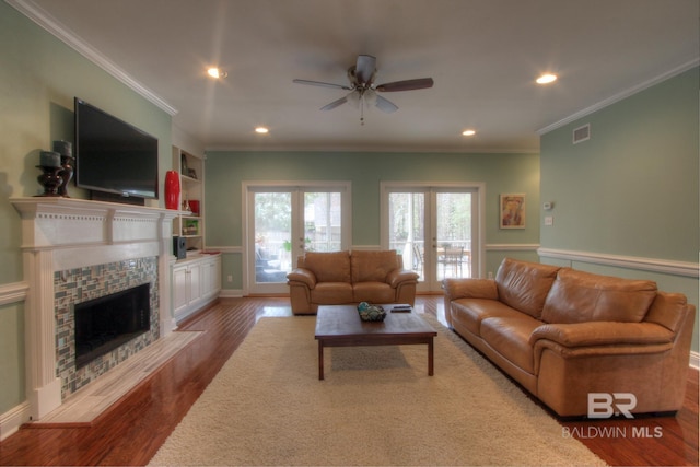 living area featuring a fireplace with flush hearth, visible vents, ornamental molding, and wood finished floors