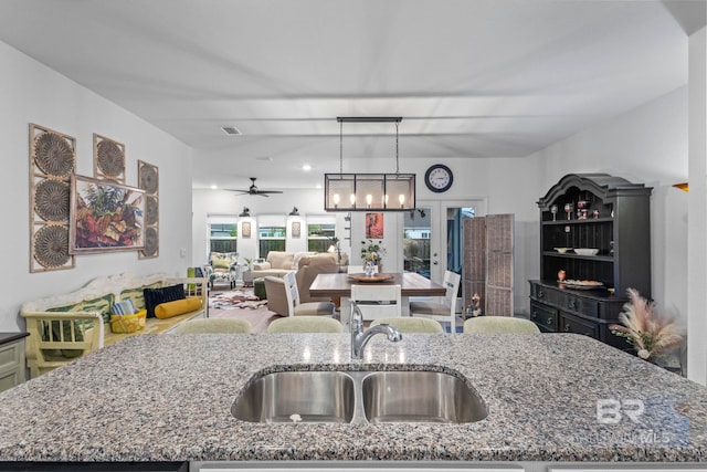 4142 Montague Dr, Gulf Shores, AL 36542 - kitchen featuring a sink, open floor plan, stone countertops, hanging light fixtures, and a center island with sink