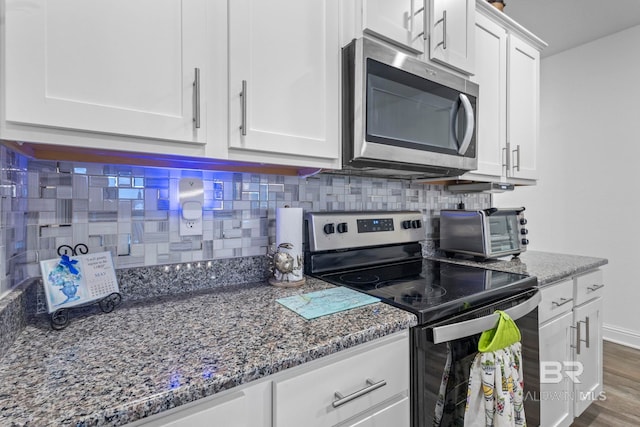 4142 Montague Dr, Gulf Shores, AL 36542 - kitchen featuring appliances with stainless steel finishes, tasteful backsplash, white cabinetry, and dark stone counters