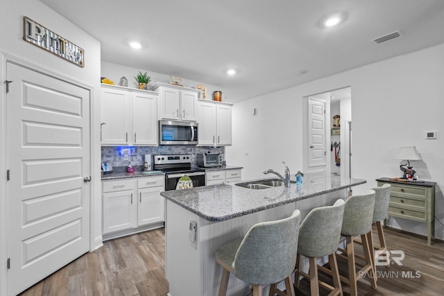 4142 Montague Dr, Gulf Shores, AL 36542 - kitchen with stainless steel appliances, a sink, wood finished floors, a breakfast bar area, and recessed lighting