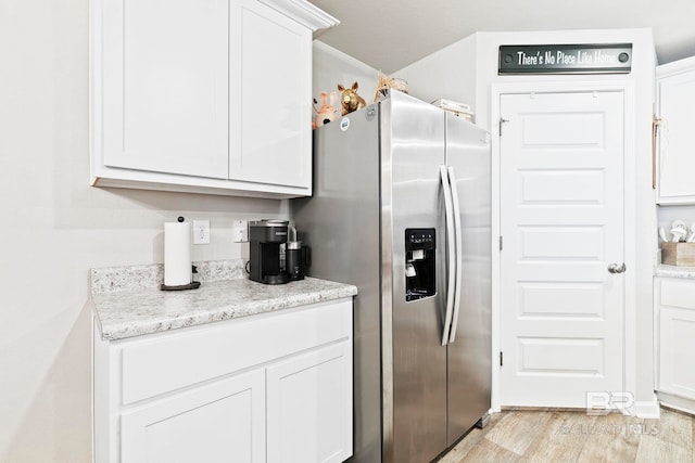 kitchen with stainless steel fridge with ice dispenser, white cabinets, light stone counters, and light wood-type flooring