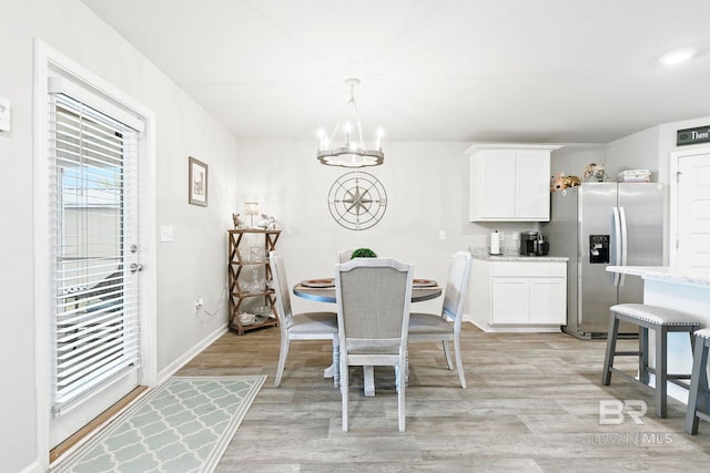 dining space featuring light hardwood / wood-style floors and an inviting chandelier