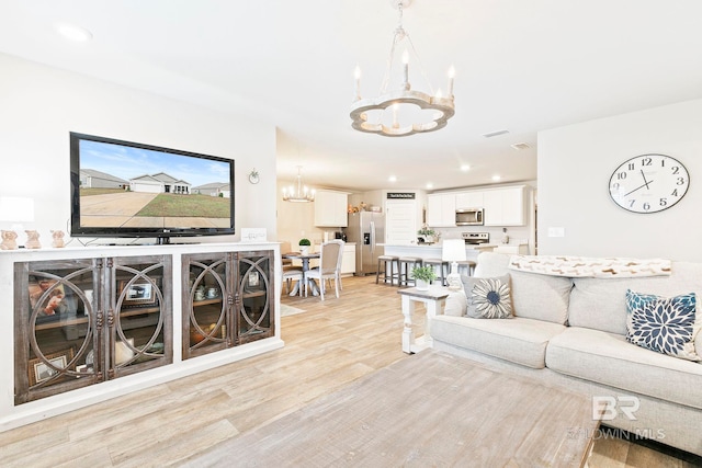 living room with light hardwood / wood-style floors and an inviting chandelier