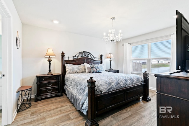 bedroom with light hardwood / wood-style floors and a notable chandelier