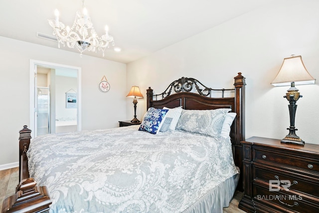 bedroom featuring a chandelier, light wood-type flooring, and ensuite bath