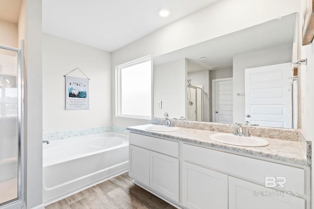 bathroom with plus walk in shower, wood-type flooring, and vanity