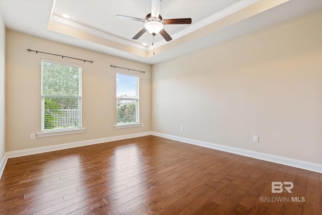 unfurnished room featuring dark hardwood / wood-style flooring, ceiling fan, ornamental molding, and a tray ceiling