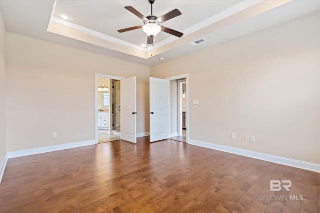 unfurnished room with a tray ceiling, crown molding, ceiling fan, and dark hardwood / wood-style floors