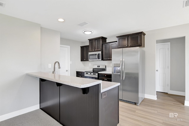 16529 Cold Mill Loop, Foley, AL 36535 - kitchen with stainless steel appliances, a breakfast bar area, light countertops, a peninsula, and dark brown cabinets