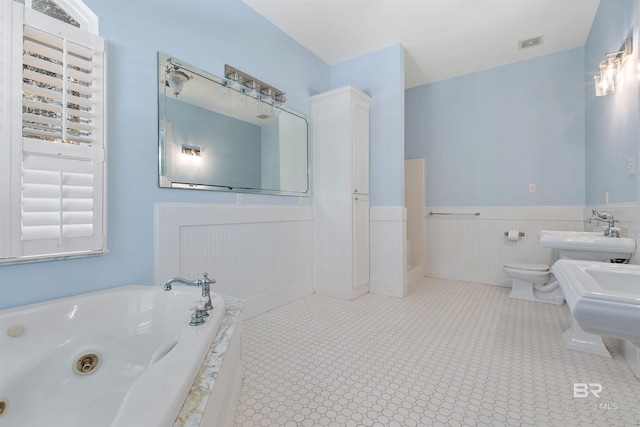 bathroom featuring a washtub, toilet, a bidet, and sink