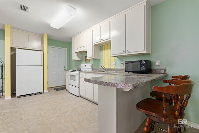 kitchen featuring a breakfast bar, white appliances, and white cabinetry