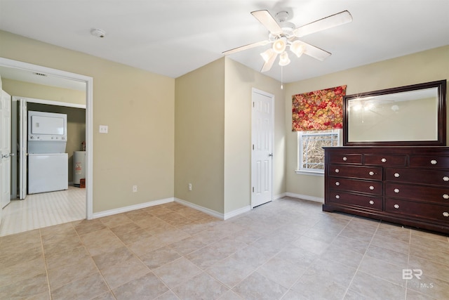 unfurnished bedroom featuring stacked washer / dryer, ceiling fan, and light tile patterned floors