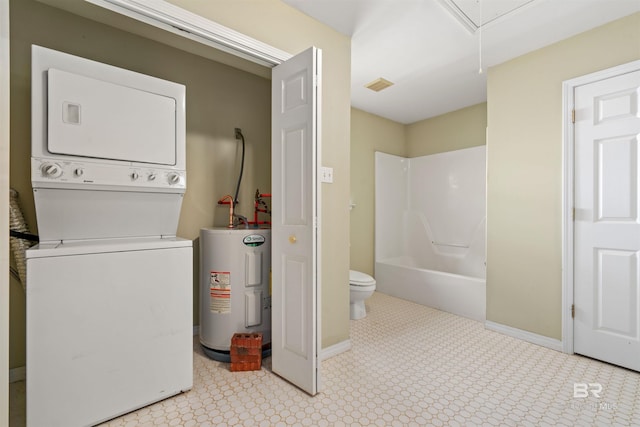 washroom with electric water heater and stacked washer and clothes dryer