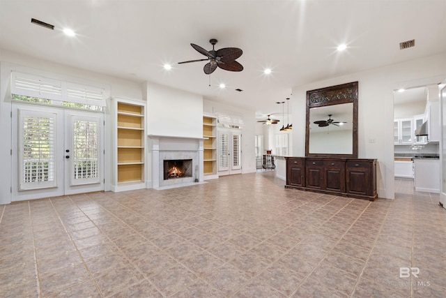 living room featuring a high end fireplace, french doors, and built in shelves