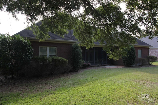 306 S Tee Dr, Fairhope, AL 36532 - view of property hidden behind natural elements with a front yard, a sunroom, brick siding, and a shingled roof
