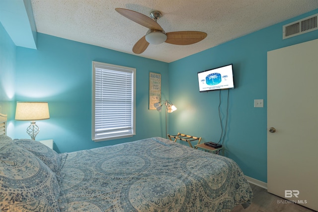 bedroom with ceiling fan, wood-type flooring, and a textured ceiling