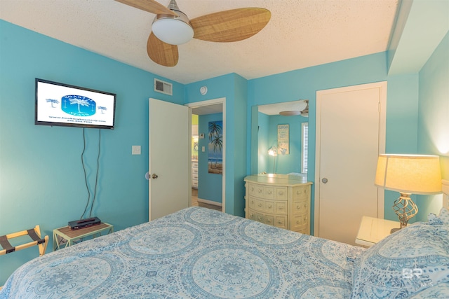 bedroom with ceiling fan and a textured ceiling