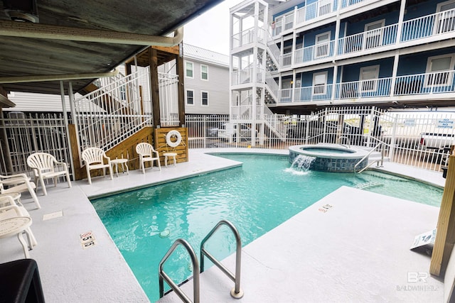 view of swimming pool featuring pool water feature, a hot tub, and a patio