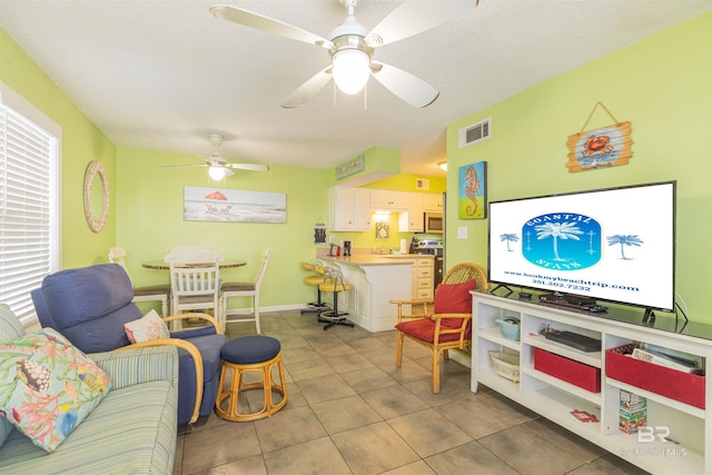 tiled living room featuring ceiling fan and a textured ceiling