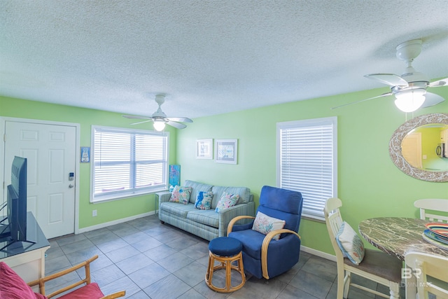 living room with ceiling fan, light tile patterned floors, and a textured ceiling