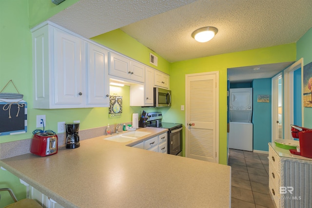 kitchen with stainless steel appliances, sink, kitchen peninsula, white cabinetry, and stacked washer / drying machine