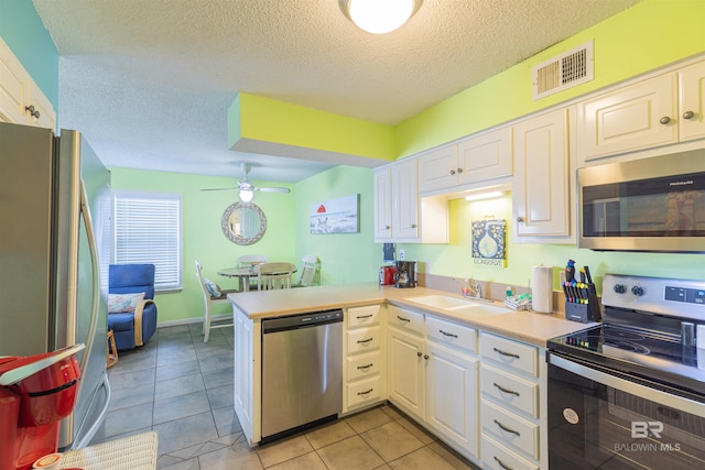 kitchen with ceiling fan, light tile patterned flooring, kitchen peninsula, white cabinetry, and appliances with stainless steel finishes