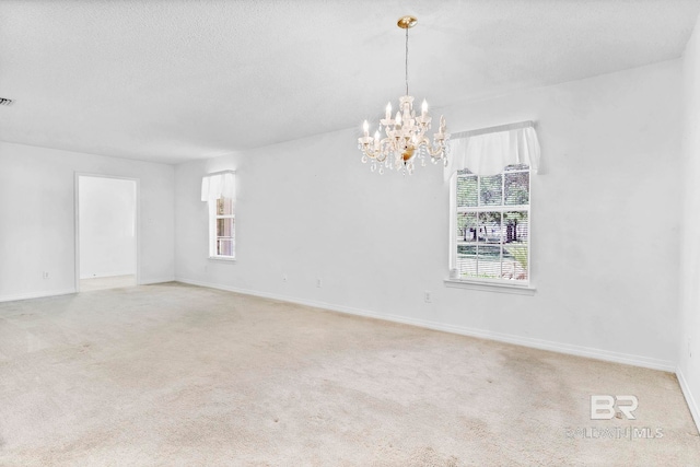 carpeted empty room with a wealth of natural light, a chandelier, baseboards, and a textured ceiling