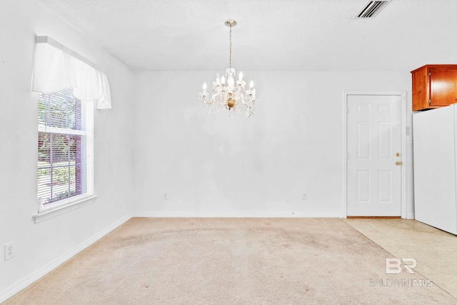 empty room with baseboards, an inviting chandelier, visible vents, and light colored carpet