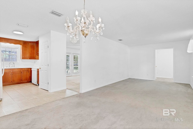 unfurnished dining area with plenty of natural light, a chandelier, visible vents, and a sink
