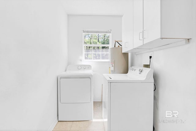 clothes washing area with washer and dryer, water heater, cabinet space, and baseboards
