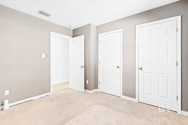 unfurnished bedroom featuring light colored carpet, visible vents, and baseboards