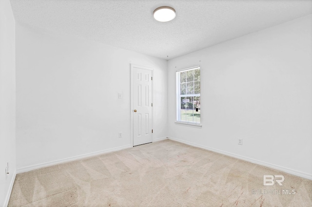 carpeted spare room with baseboards and a textured ceiling