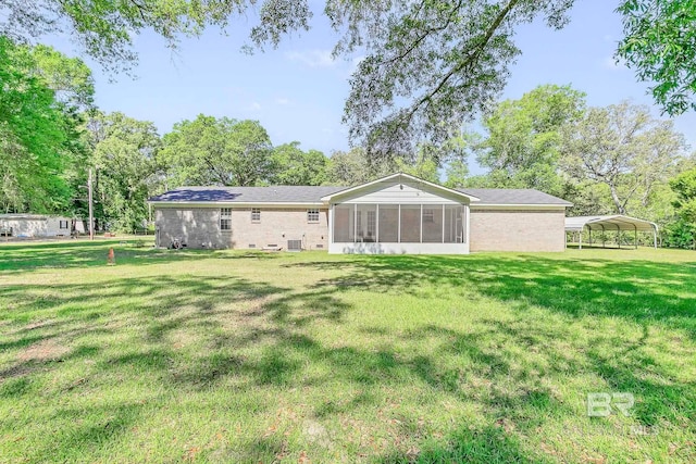 rear view of house with a sunroom, a carport, and a lawn