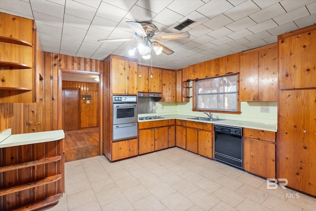 kitchen featuring sink, wooden walls, black dishwasher, gas stovetop, and stainless steel oven