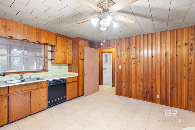 kitchen featuring sink, ceiling fan, dishwasher, and wood walls