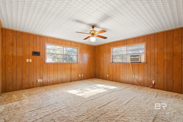 spare room with carpet, cooling unit, ceiling fan, and wood walls