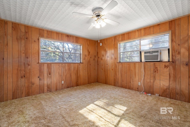 carpeted spare room featuring ceiling fan, cooling unit, and wooden walls