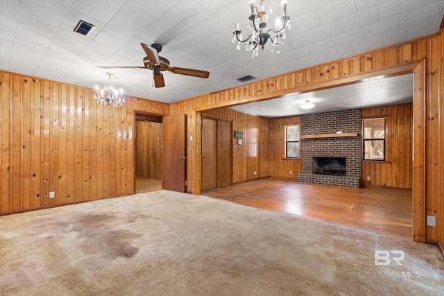 unfurnished living room with a brick fireplace, ceiling fan with notable chandelier, and light carpet