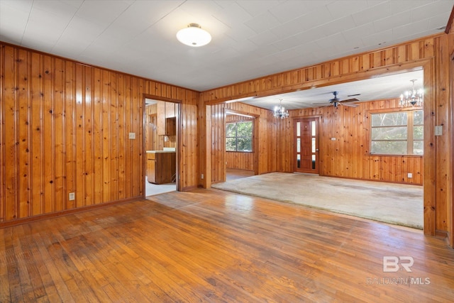 unfurnished room with hardwood / wood-style floors, an inviting chandelier, and wood walls