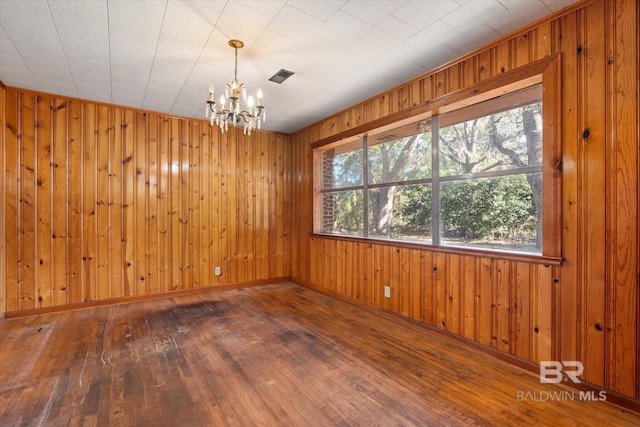 spare room with wood-type flooring and an inviting chandelier