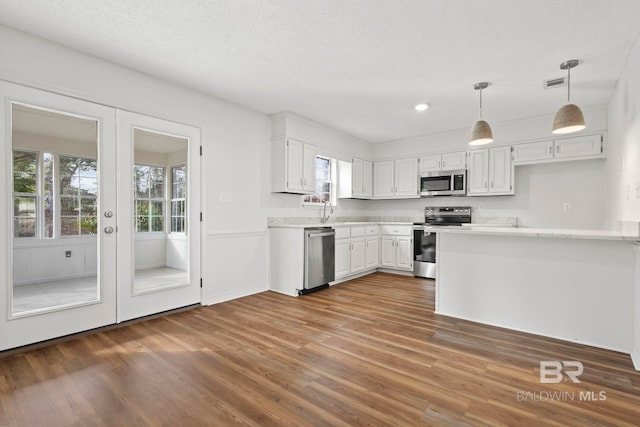 kitchen with white cabinetry, appliances with stainless steel finishes, a healthy amount of sunlight, and dark hardwood / wood-style flooring