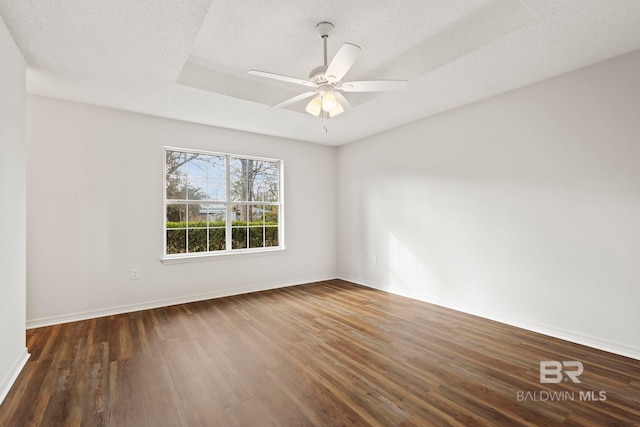 spare room with a raised ceiling, ceiling fan, dark hardwood / wood-style floors, and a textured ceiling