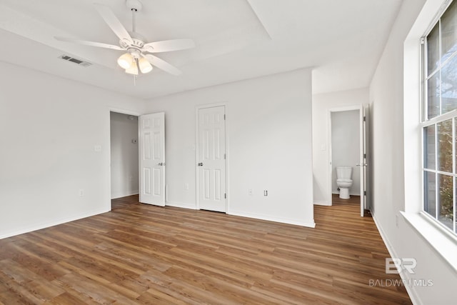 unfurnished bedroom featuring multiple windows, wood-type flooring, and ceiling fan