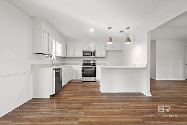 kitchen with sink, appliances with stainless steel finishes, dark hardwood / wood-style floors, pendant lighting, and white cabinets