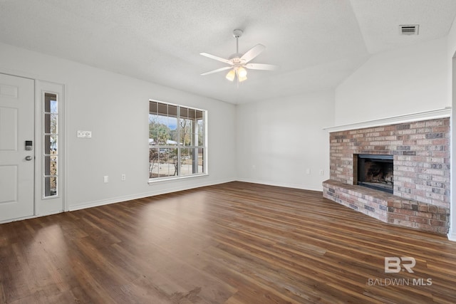 unfurnished living room featuring a brick fireplace, a textured ceiling, and dark hardwood / wood-style flooring