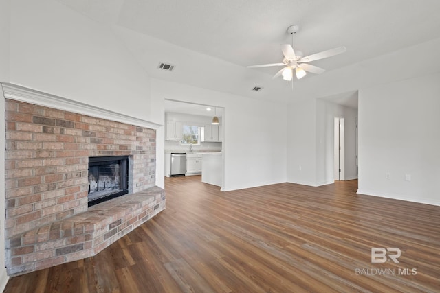 unfurnished living room with dark hardwood / wood-style flooring, a brick fireplace, sink, and ceiling fan